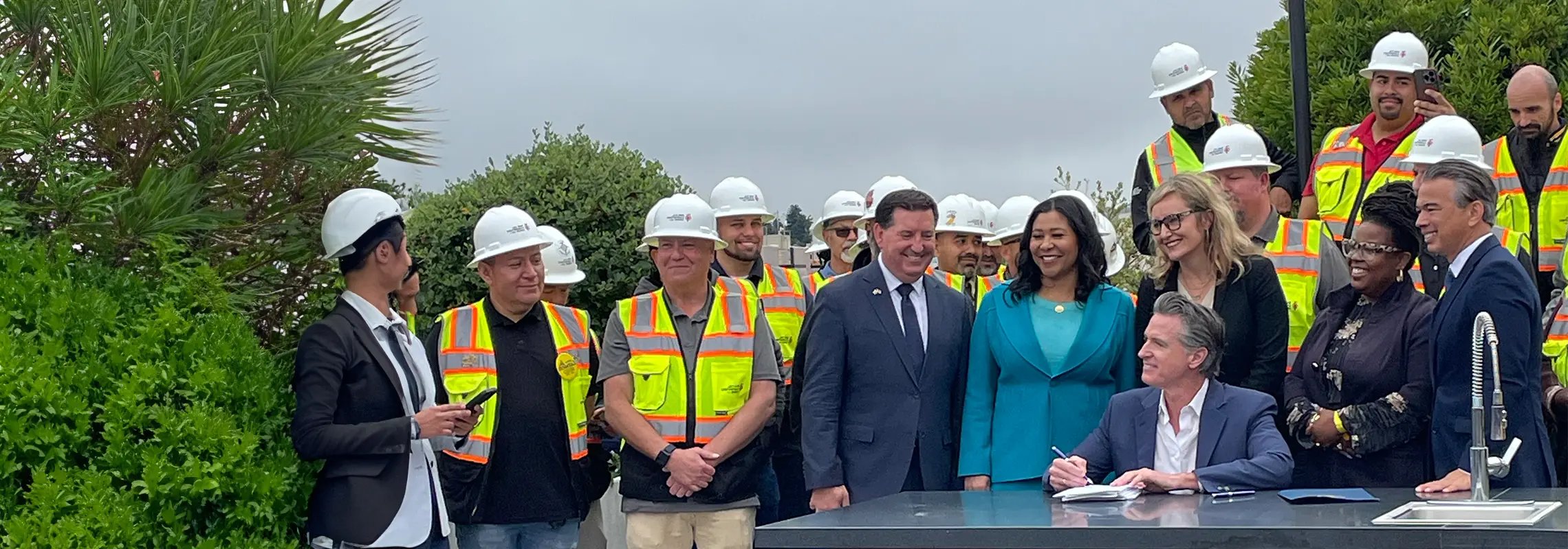 Governor Newsom signing bills in front of dignitaries and audience members.