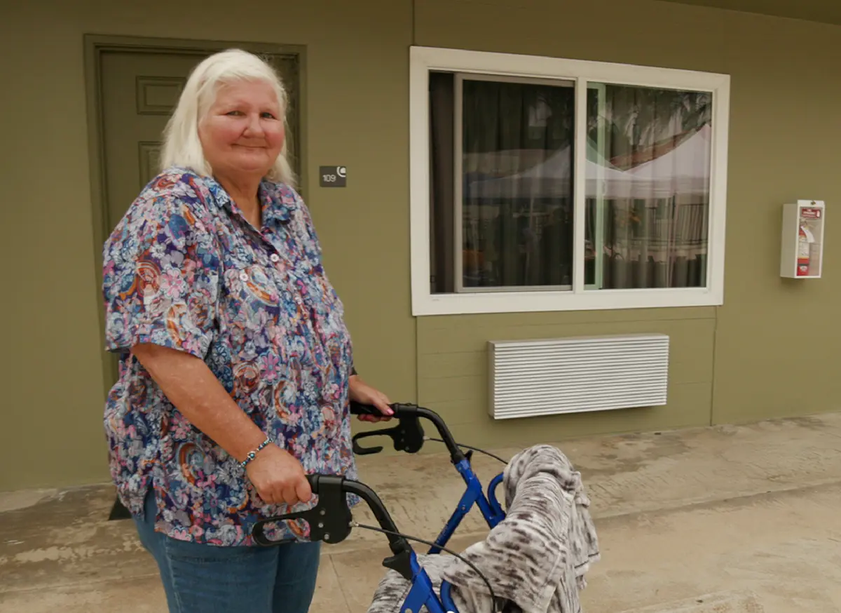 lady with walker smiling in front of her new apartment